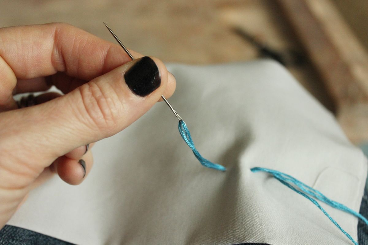 Pull the needle and thread through the fabric.